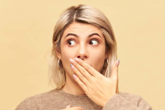 causes-of-bad-breath (1) woman covering mouth to remove the cause of bad breath