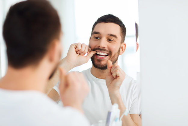 man flossing after learning the benefits of flossing daily