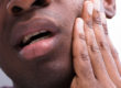 a man holding his sensitive tooth wondering how does tooth decay develop
