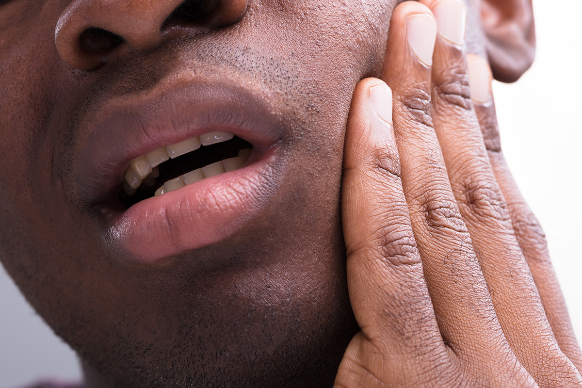 a man holding his sensitive tooth wondering how does tooth decay develop