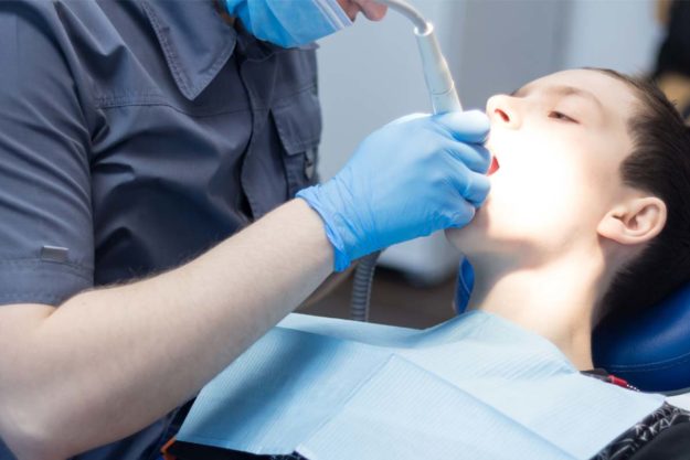 benefits-of-dental-sealants dentist helping young boy get the benefits of dental sealants